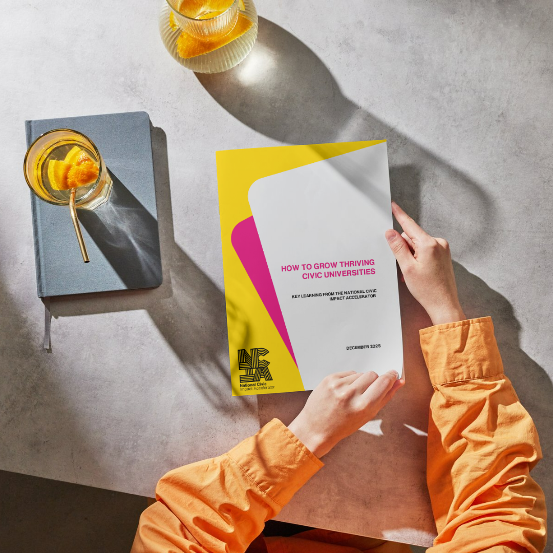 A person in an orange shirt holds a colourful NCIA report titled "How to Grow Thriving Civic Universities" on a light grey table next to a notebook and a glass of orange drink.