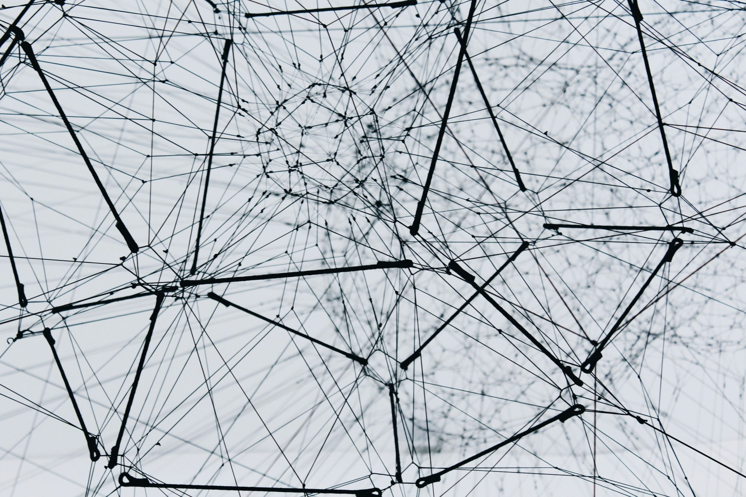 Abstract black-and-white network of intersecting lines and nodes forming a complex web pattern.